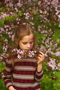 Spring portrait of a six year old girl standing under the blooming pink cherry tree