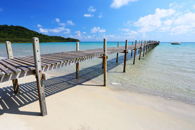 Wooden posts on beach against sky