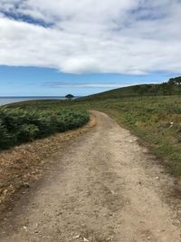 Dirt road along landscape against sky