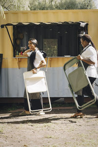 Female entrepreneurs with chairs walking by food truck