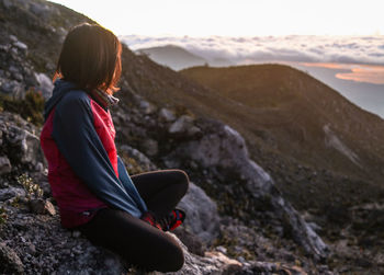 Side view of woman sitting on rock