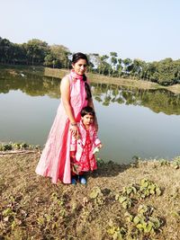 Portrait of smiling girl standing by lake against sky