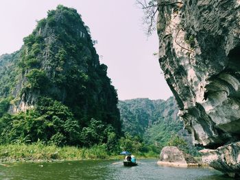 Man on boat against trees against clear sky