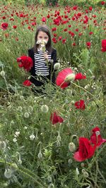 Portrait of young woman standing amidst plants on field