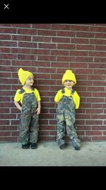 Full length of a boy standing against brick wall