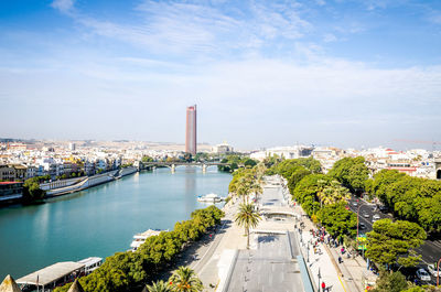 View of city at waterfront against cloudy sky