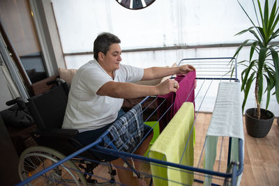 A disabled person on a wheelchair washes laundry