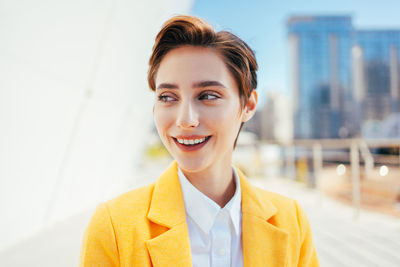 Portrait of young businesswoman standing against building