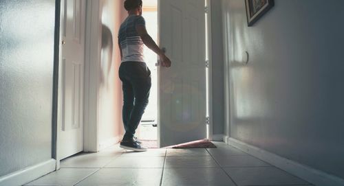 Rear view of man opening door while standing at entrance