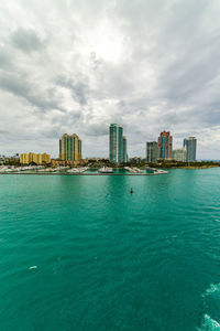 Sea by cityscape against sky