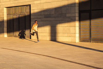 Full length of man walking on street against building