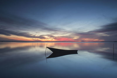 Boat moored in sea against sky during sunset