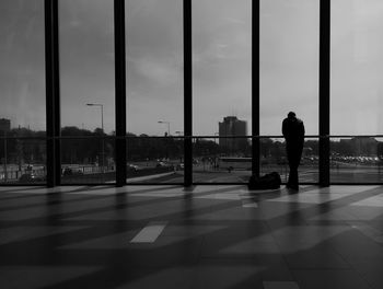 Man standing against glass window