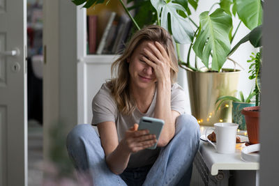 Shy woman using mobile phone at home