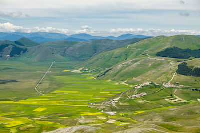 High angle view of green landscape and mountains against sky in castelluccio, umbria 