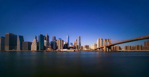 Brooklyn bridge over east river against clear blue sky in city