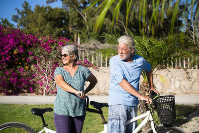 Senior couple riding bicycle against plants