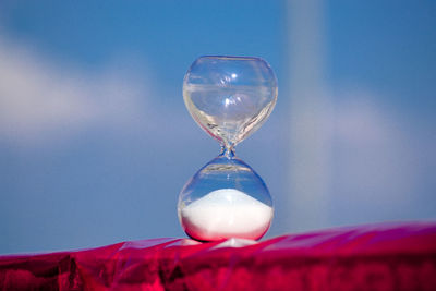 Close-up of hourglass against blue sky