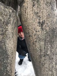 Woman standing by tree trunk in snow