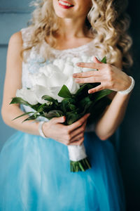 Midsection of woman wearing blue dress holding bouquet