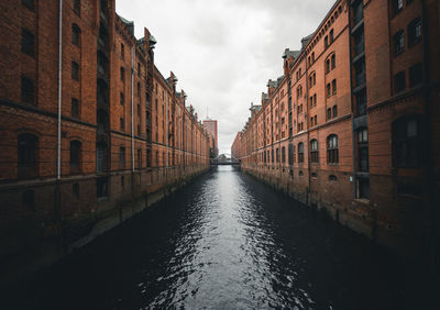 Canal amidst buildings in city against sky