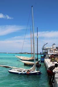 Sailboats moored in sea against sky