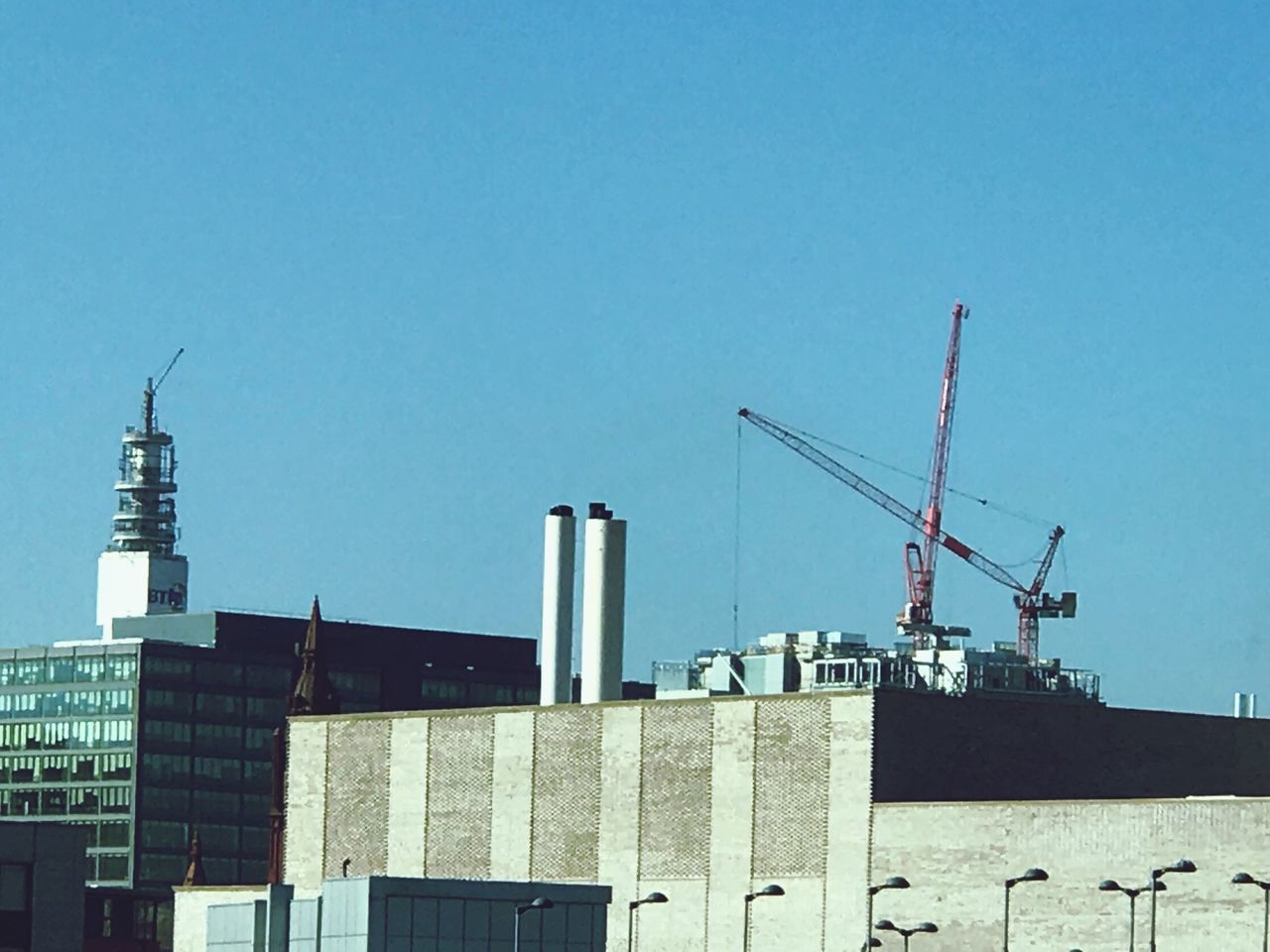 CRANES AT CONSTRUCTION SITE AGAINST SKY