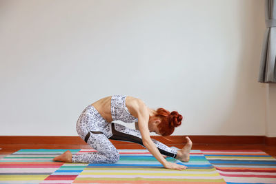 Full length of young woman exercising at home