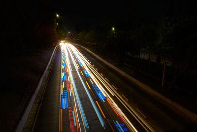 From above of colorful traffic light trails along road in dark city at night in long exposure