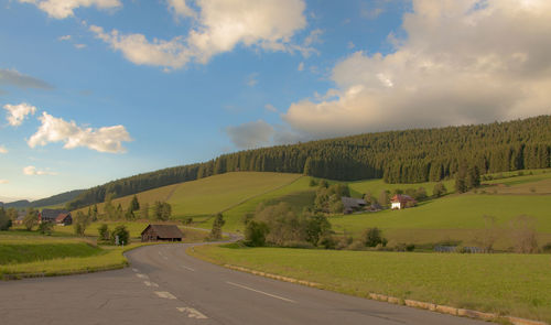 Scenic view of road along landscape and trees against sky