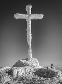 Close-up of cross on rock against sky during winter