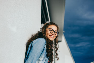 Smiling young woman against wall