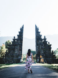 Rear view of woman standing outside temple against clear sky