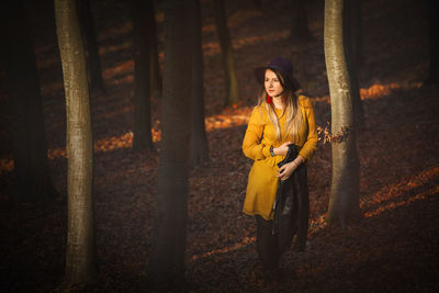 Portrait of woman standing by tree in forest