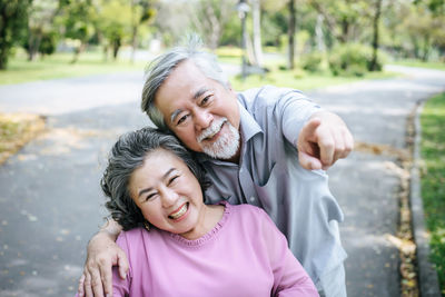 Portrait of smiling senior couple on road at park