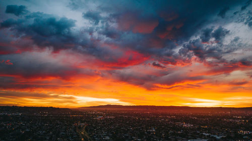 Scenic view of dramatic sky over city during sunset