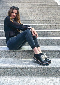Portrait of a smiling young woman sitting on staircase
