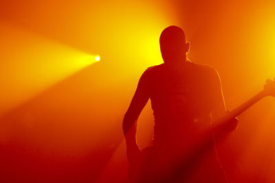 Silhouette woman standing by illuminated orange during sunset