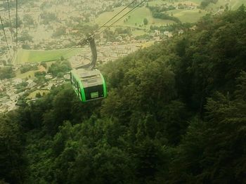 Overhead cable car amidst trees against sky