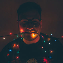 Portrait of young man in illuminated eyeglasses at night