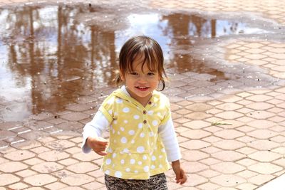 Portrait of smiling girl standing on footpath