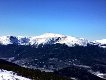 Scenic view of snow covered mountains against blue sky
