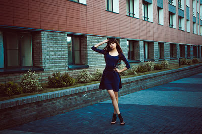 Full length portrait of young woman standing in city