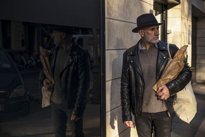 Adult man in hat holding bread and vegetable bag on street. madrid, spain