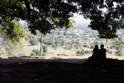 Rear view of silhouette people sitting on land against sky