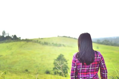 Rear view of woman standing on field against sky