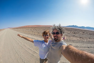 Portrait of smiling mature couple standing on desert road