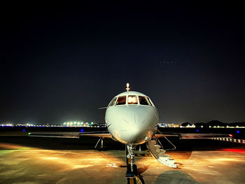Airplane on airport runway against sky at night
