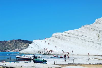 Panoramic view of people on landscape against clear blue sky