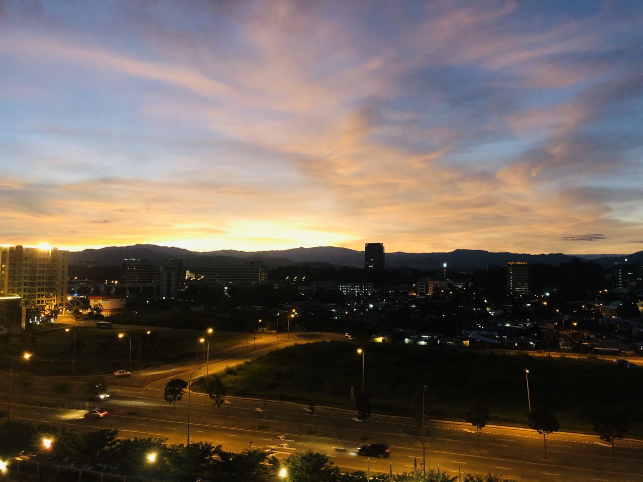 HIGH ANGLE VIEW OF ILLUMINATED CITY BUILDINGS DURING SUNSET